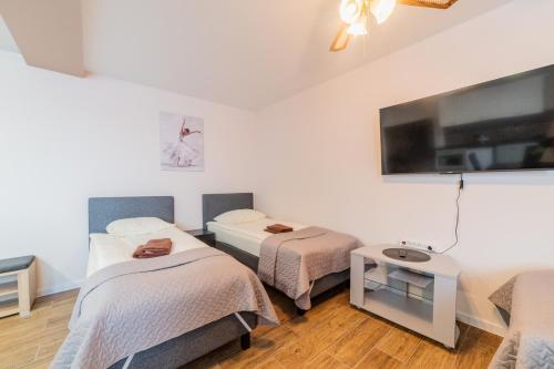 a room with three beds and a flat screen tv at Svečių namai Imperija in Šiauliai
