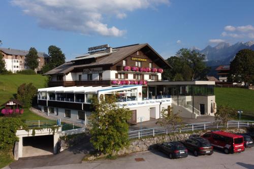 un bâtiment avec des voitures garées dans un parking dans l'établissement Hotel-Café Perner, à Schladming