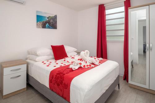 a bedroom with a bed with a red and white blanket at La fleur des îles - Maison Climatisé pour 4 in Morne-à-lʼEau