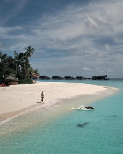 a person walking on a beach in the ocean at Park Hyatt Maldives Hadahaa in Gaafu Alifu Atoll
