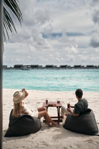a man and a woman sitting on the beach at Park Hyatt Maldives Hadahaa in Gaafu Alifu Atoll