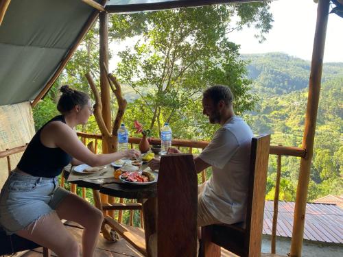 a man and woman sitting at a table with a plate of food at Ella Soul Nest Glamping Tent for Nature Lovers in Ella