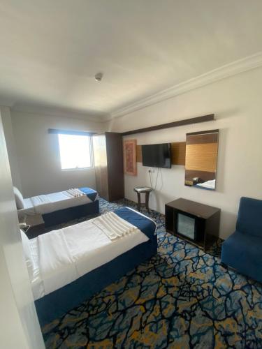 a hotel room with two beds and a blue chair at فندق الدرع - شركة درع بن سليمان الدرع in Quai