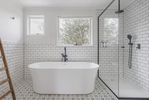 Un baño blanco con bañera y ventana. en La Belle Vie - Boutique Country Escape near Wineries, en Red Hill