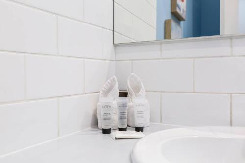 Un baño blanco con lavabo y dos secadores de pelo. en Mia's Place - Victorian Terrace with Modern Comfort, en Melbourne