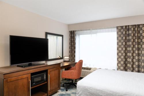 a hotel room with a bed and a television on a desk at Hampton Inn Portland East in Portland