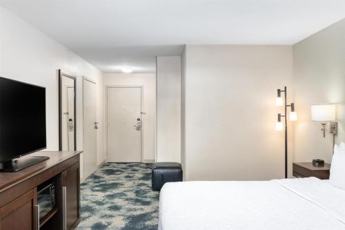 a hotel room with a bed and a flat screen tv at Hampton Inn Portland East in Portland