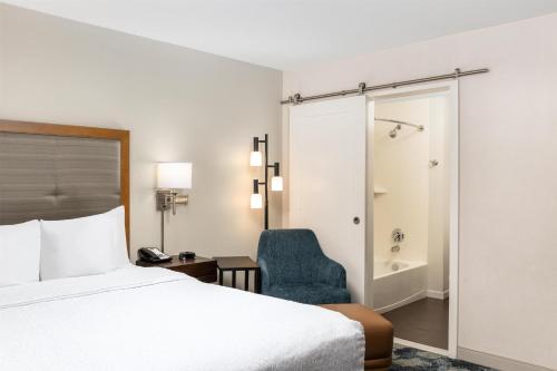 a hotel room with a bed and a chair at Hampton Inn Portland East in Portland