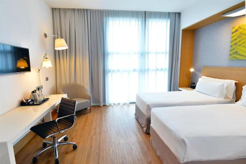 a hotel room with two beds and a desk at Hilton Garden Inn Milan North in Milan