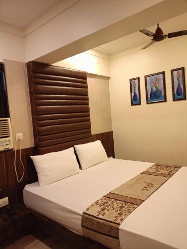 a bedroom with a bed with white sheets and a brown headboard at Hotel Diamora Residency in Thane