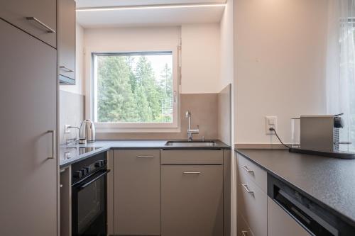 a kitchen with a sink and a window at Zuhause in den Alpen Ihre Ferienwohnung mit Hallenbad und Sauna in Lenzerheide