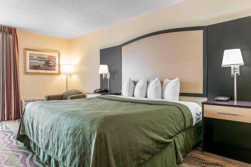 a hotel room with a bed with a green bedspread at Quality Inn Conference Center Logansport in Logansport