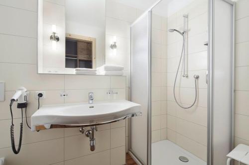 a white bathroom with a sink and a shower at Gasthof Salzstadl in Reutte