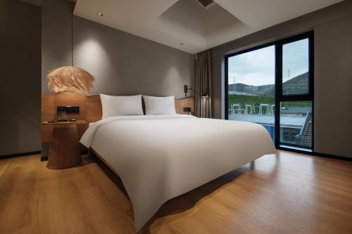 Koktokay可可托海的梦·非遗度假酒店的房间里有一张白色的大床，窗户很大