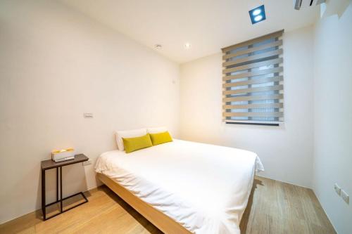 a small bedroom with a white bed with yellow pillows at 慶東雙包棟招待所 兩棟可選擇包層包棟 可住4-70人 團體聚會首選 in Tainan
