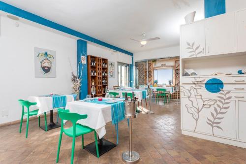 a restaurant with white tables and green chairs at Sirina Tao Beach in Taormina