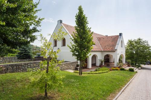 a white house with a stone wall at Figula Vendégház in Balatonfüred