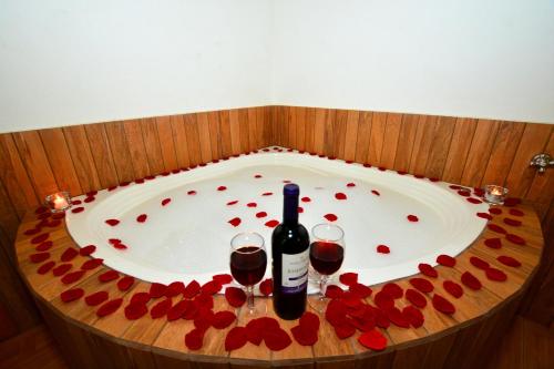 a bath tub with a bottle of wine and two glasses at Pousada Cantinho Colibri in Monte Verde