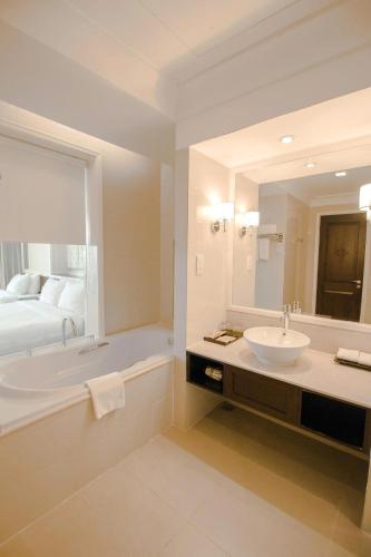 a bathroom with a sink and a tub and a bed at La Sapinette Hotel Dalat in Da Lat
