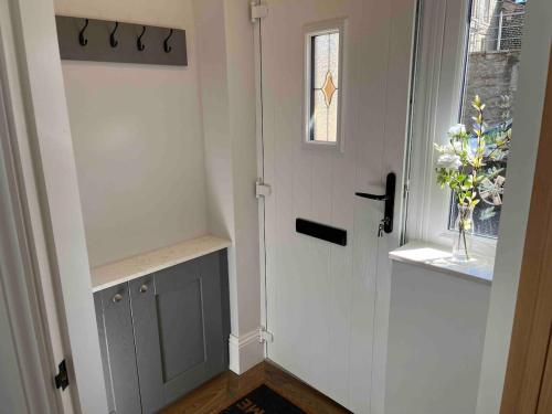 a hallway with a white door with a vase of flowers at 4 Mulberry Green , Waterfoot , Rossendale, Lancs in Newchurch