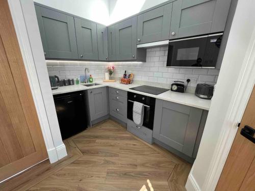 a kitchen with gray cabinets and black appliances at 4 Mulberry Green , Waterfoot , Rossendale, Lancs in Newchurch