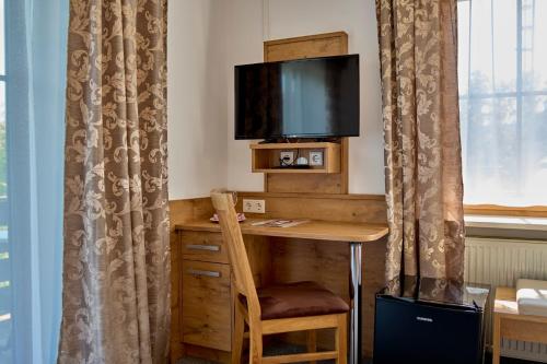 a room with a desk with a tv and a chair at Gasthof Pension Fischerstüberl in Blaibach