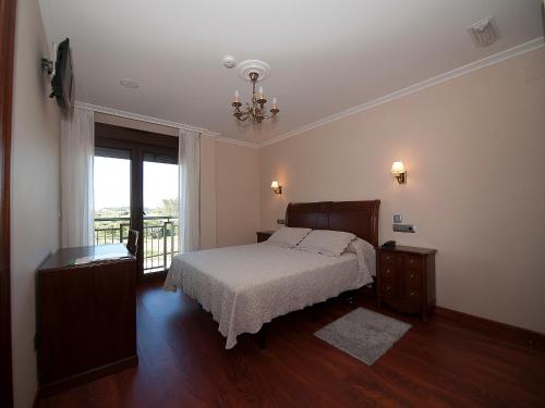 a bedroom with a bed and a large window at Pensión Residencia A Cruzán in Noalla