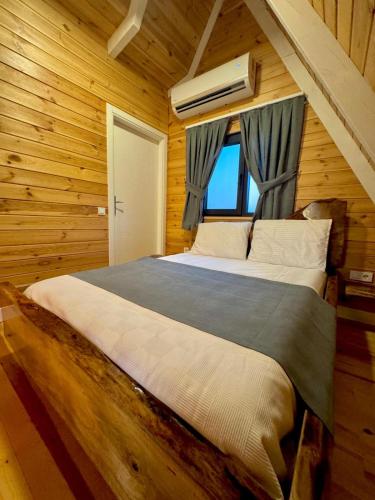 a bedroom with a large bed in a wooden room at Armoni Life Bungalov in Yanık