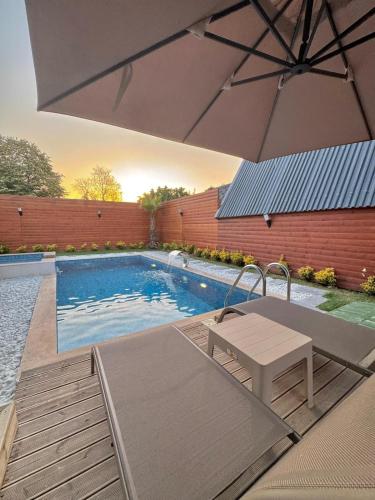 a swimming pool with a table and an umbrella at Armoni Life Bungalov in Yanık