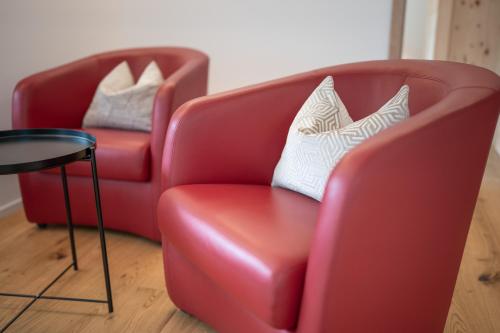 two red chairs and a table in a room at Zuhause in den Alpen Ihre Ferienwohnung mit Hallenbad und Sauna in Lenzerheide