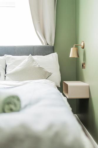 a bed with white sheets and a lamp next to a window at HOME1 - Augarten City Stay Boutique Hostel in Vienna