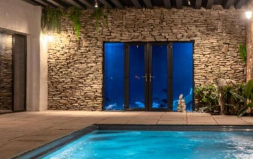a swimming pool in front of a building with blue doors at Sherwood Lodge in Wellow