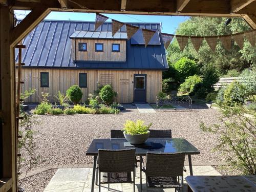 a patio with a table and chairs and a barn at Larchwood Lodge in Ellon