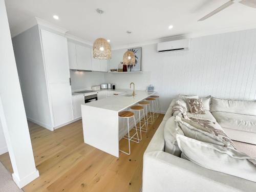 a white kitchen and living room with a couch at Coastal Bliss at Shoal Bay in Shoal Bay