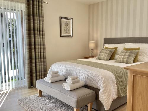 a bedroom with a large bed with towels on a bench at Larchwood Lodge in Ellon