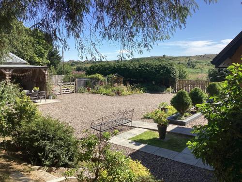 a garden with a bench in the middle at Larchwood Lodge in Ellon