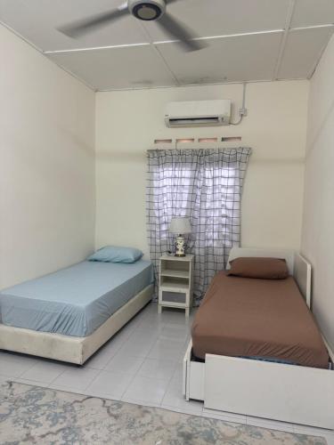 a bedroom with two beds and a ceiling fan at Homestay Mr in Temerloh