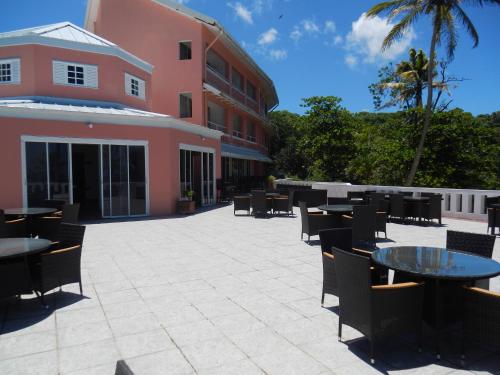 a patio with tables and chairs in front of a building at Blue Haven Hotel - Bacolet Bay - Tobago in Scarborough