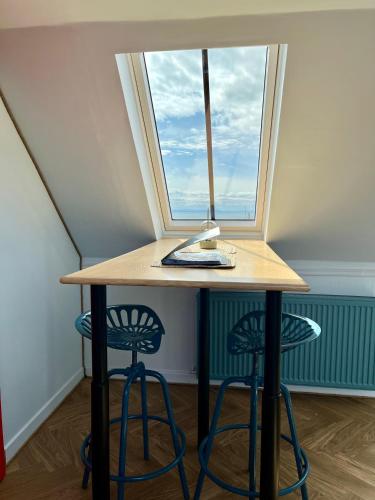 a table with two stools and a window at The Blue Loft in Anstruther