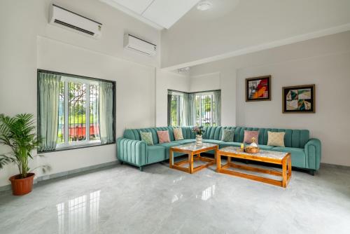a living room with a blue couch and a table at Villa Azure Bliss by Riviera Hospitality in Shāhāpur