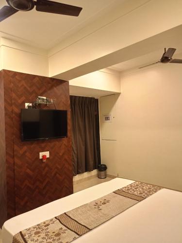 a room with a bed and a tv on a wall at Hotel Diamora Residency in Thane