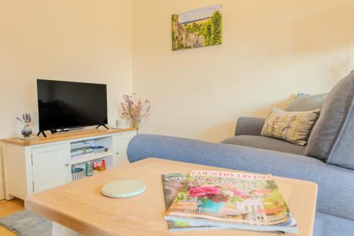 a living room with a couch and a coffee table at The Little Stable - Cosy 1 Bed Cottage in Burford in Swinbrook