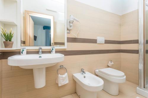 a bathroom with a sink and a toilet and a mirror at Sirina Tao Beach in Taormina