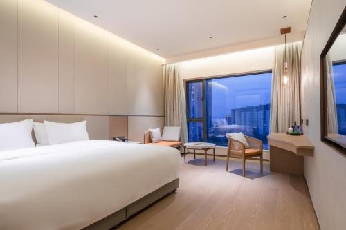 a hotel room with a bed and a large window at NARADA Fuzhou Fujian Hotel in Fuzhou