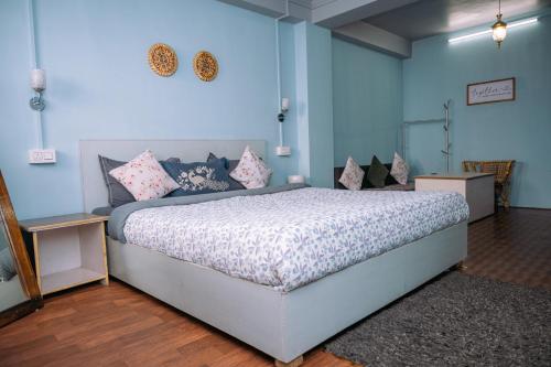 a bedroom with a large bed in a blue room at Monratino The snow roost- 10 mins walking distance from mall road- Attached balcony with Kanchenjunga Mountain View-Kitchen available in Darjeeling