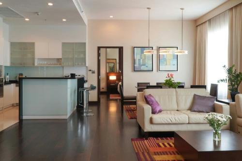 a living room with a couch and a kitchen at Marriott Executive Apartments Sukhumvit Park, Bangkok in Bangkok