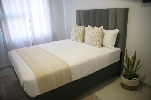 une chambre avec un lit avec des draps blancs et des oreillers dans l'établissement Sarona Habitat Urban Escape 1 Bedroom Apartment, à Gaborone