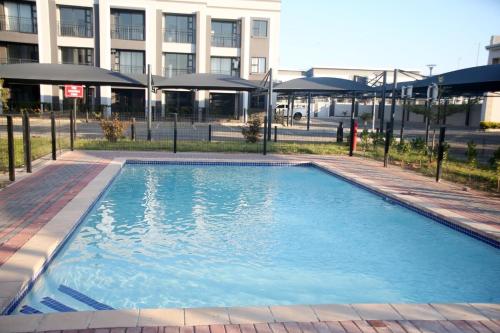 une grande piscine bleue devant un immeuble dans l'établissement Sarona Habitat Urban Escape 1 Bedroom Apartment, à Gaborone