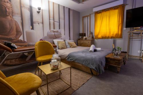 a bedroom with a bed and chairs and a television at 50 Nuances Zen - Love Room à Rouen in Rouen