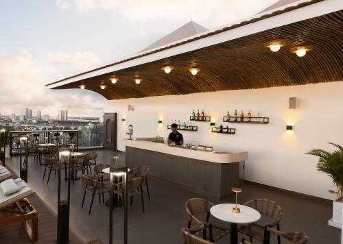 a restaurant with tables and chairs and a bar at Bassac Signature Hotel & Residence in Phnom Penh